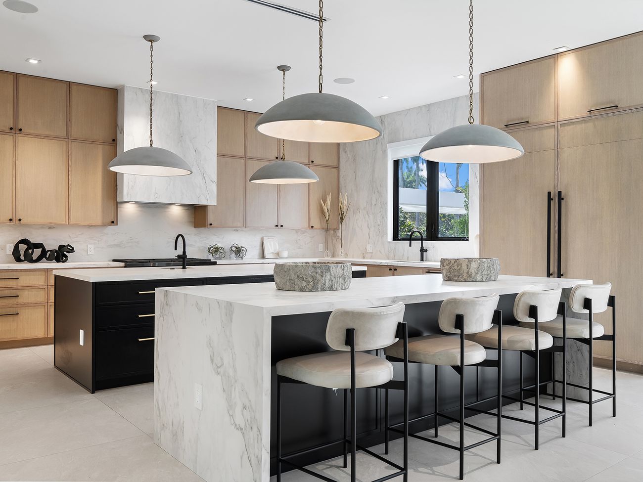 Kitchen with white-oak cabinetry and marble waterfall island on a black base