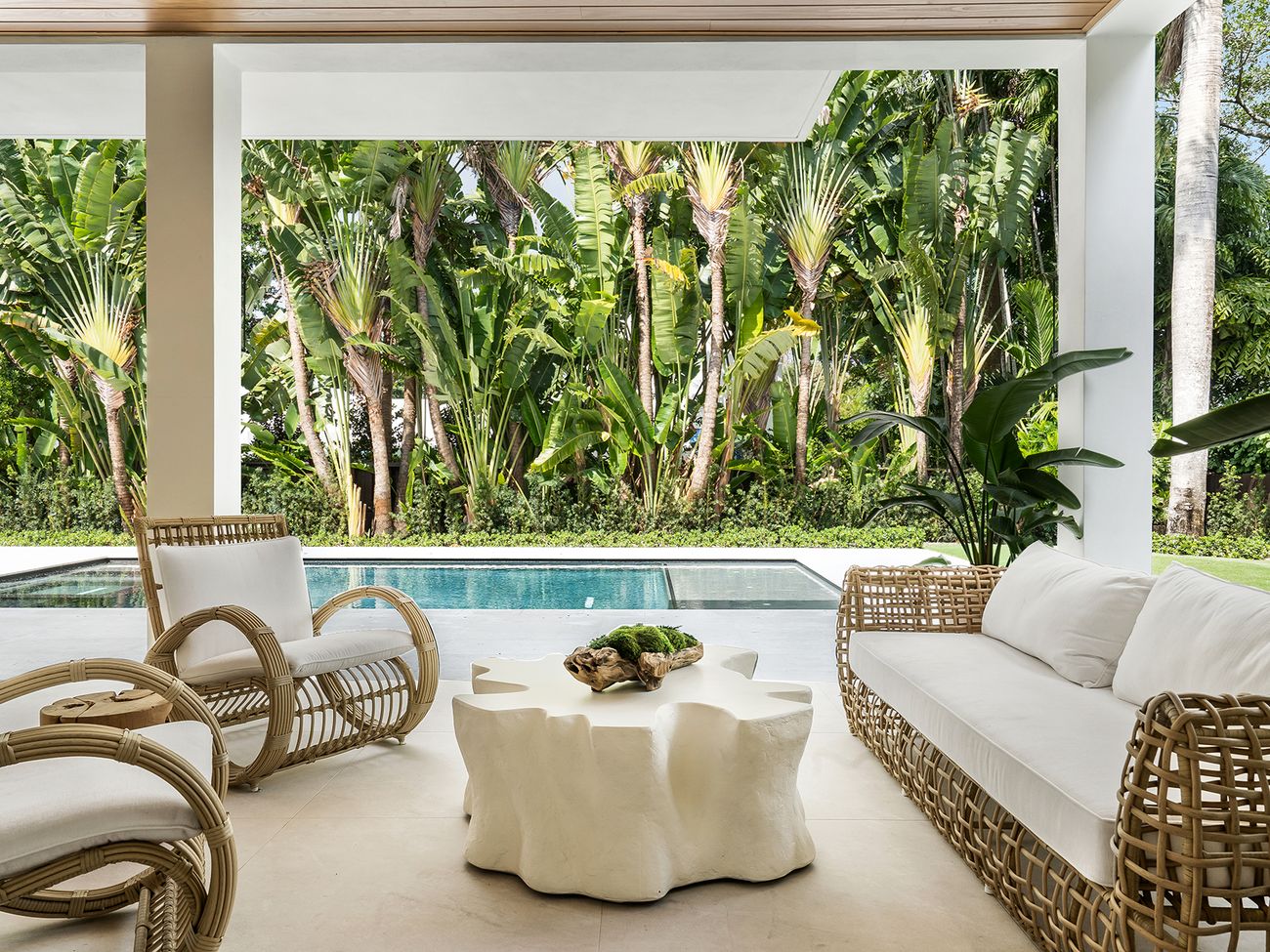 Covered terrace with rattan furniture, pool and tropical garden
